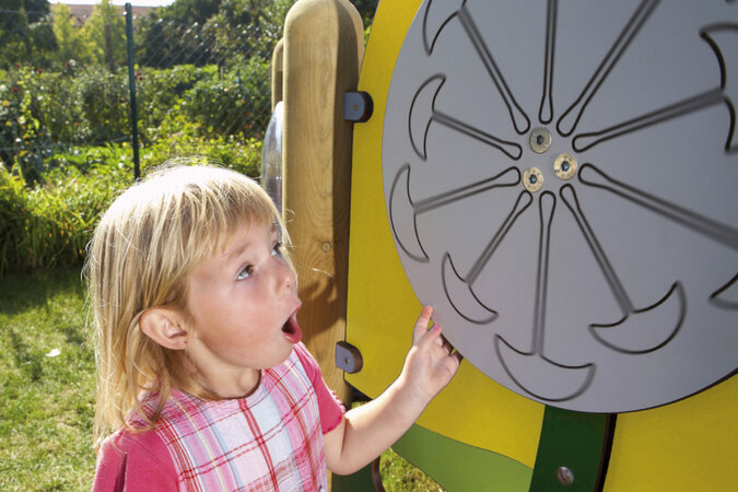 Speeltoestel voor kinderopvang van eibe - klein meisje draait aan een speelwiel op de gele eibe speelset