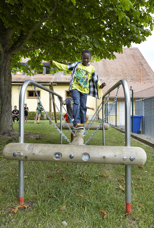 Schoolspeelplaats planning - leerling balanceert op eibe speeltoestel op de speelplaats.